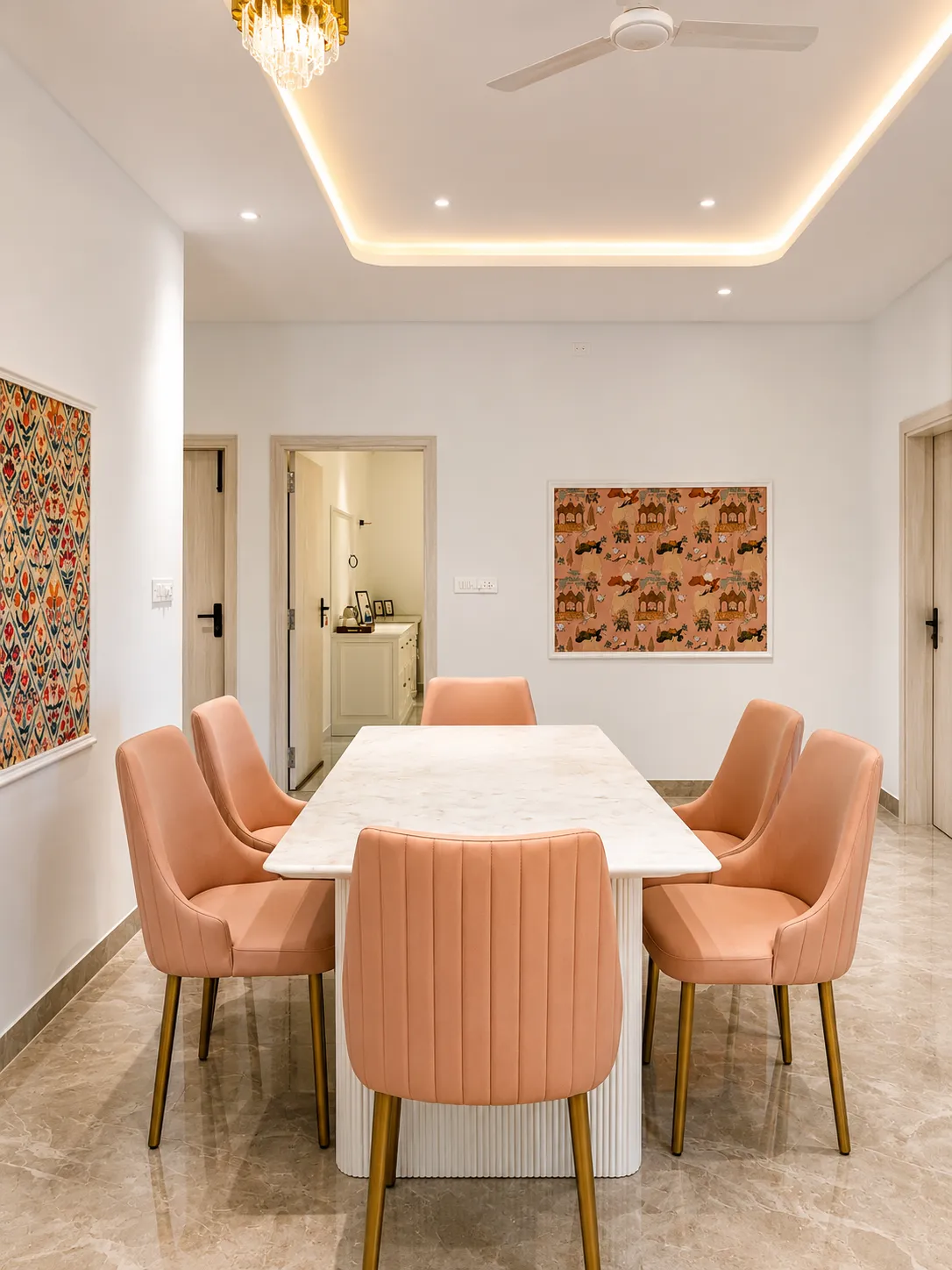 Marble dining table with blush upholstered chairs and folk-art wall pieces