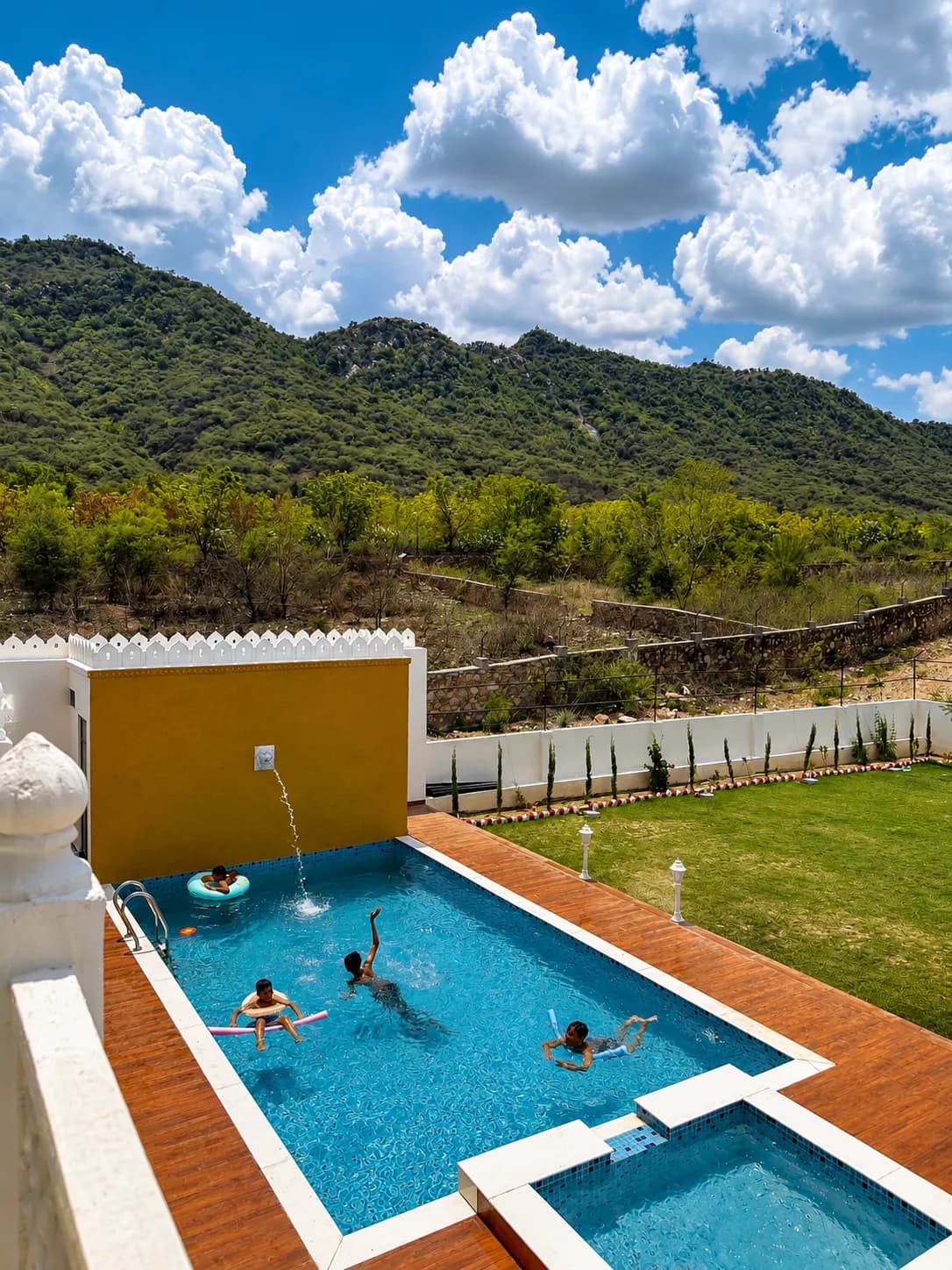 Family swimming in the garden pool beside the lawn, hills beyond