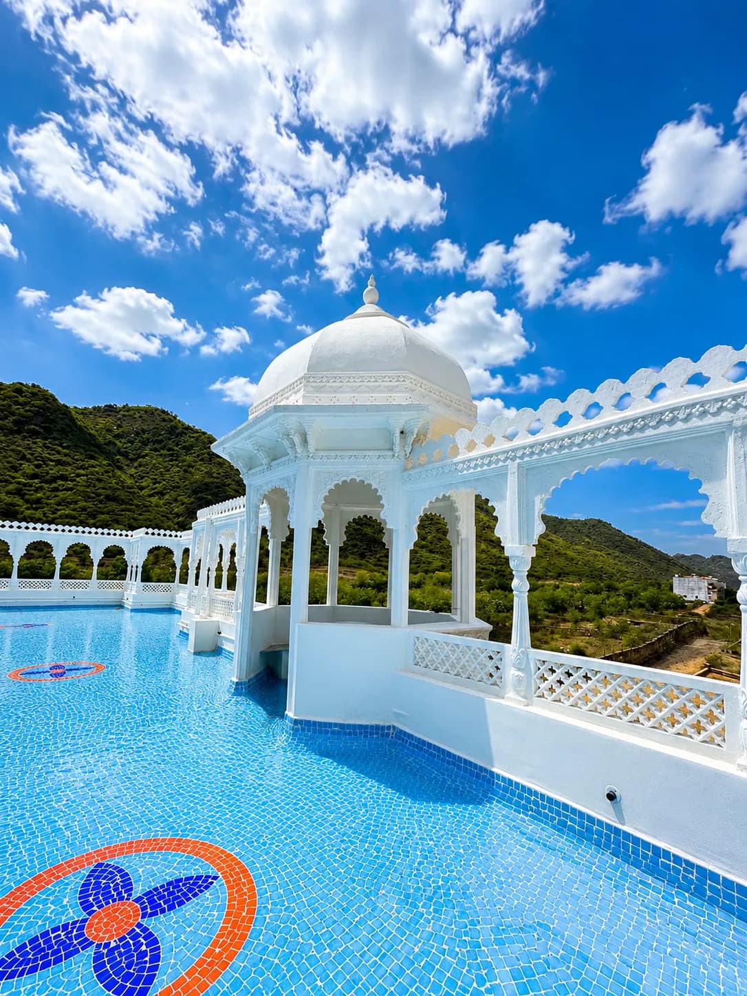 Rooftop pool with white domed chhatri pavilion overlooking the Aravalli Hills